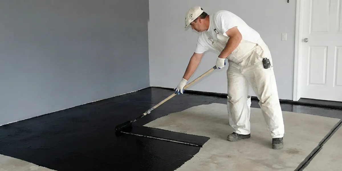basement waterproofing professional applying waterproof coating to protect a basement floor in Cambridge, MA