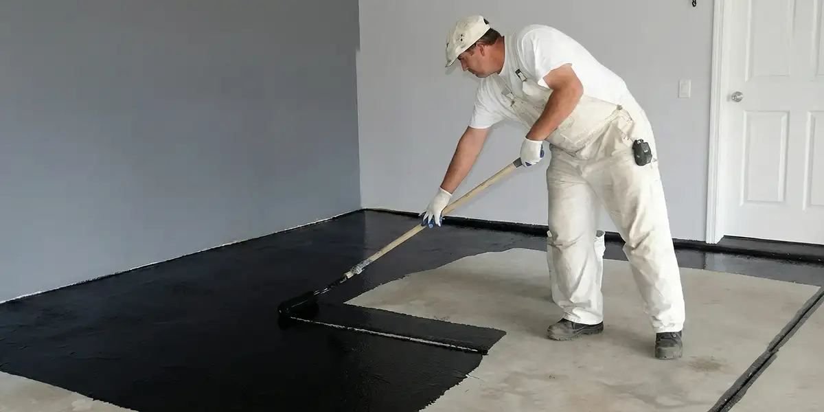 basement waterproofing professional applying waterproof coating to protect a basement floor in Cambridge, MA